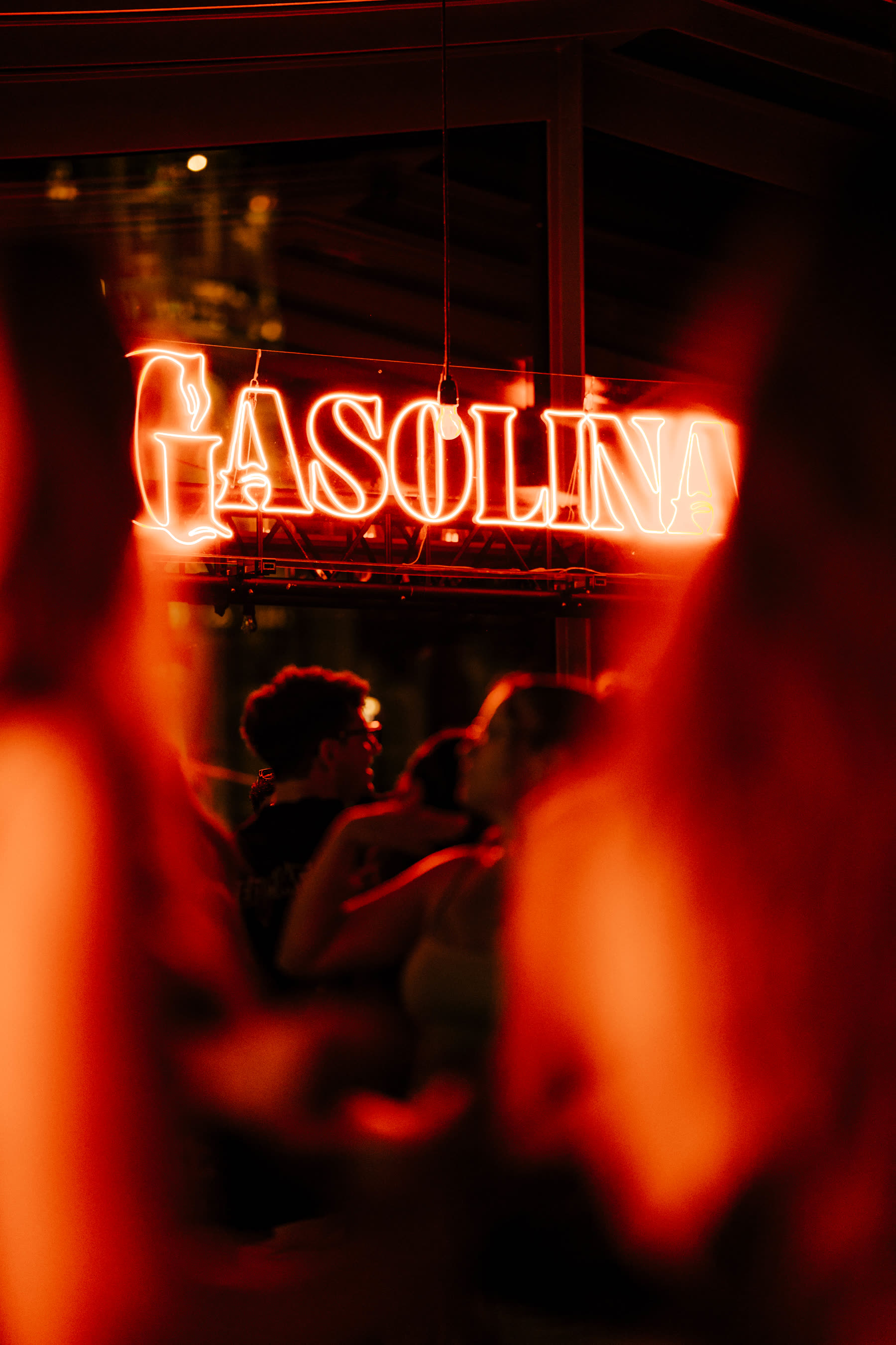 Gasolina neon seen through the crowd in deep red light